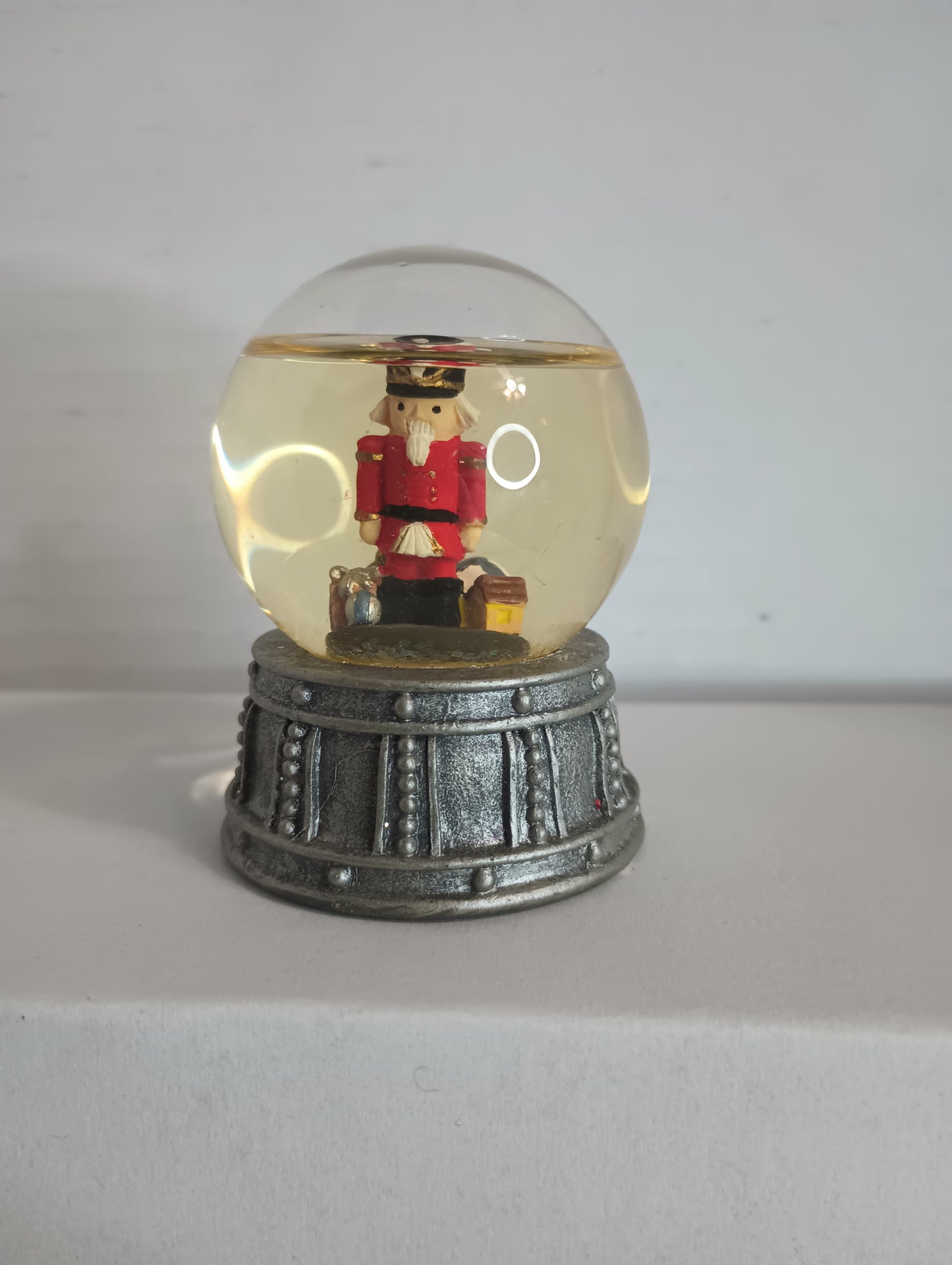 Vintage Miniature Snow Globe With Red Nutcracker and presents, ball, house On Silver Drum 2.5"